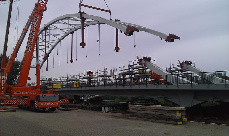 Het samenstellen van de boog op het brugdek, terwijl deze op pontons ligt, op de voorbouwlocatie